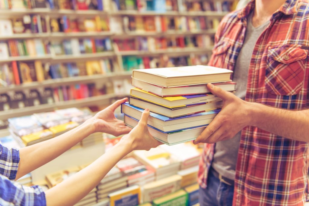 Stapel boeken wordt doorgegeven in bibliotheek