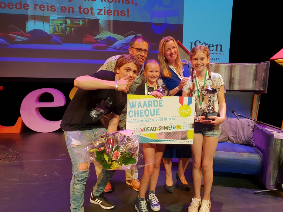 Isa op het podium met haar cheque, trofee en bloemen. 