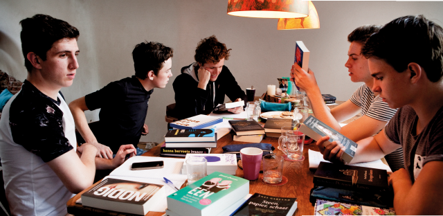 Jongeren lezen aan tafel vol boeken.