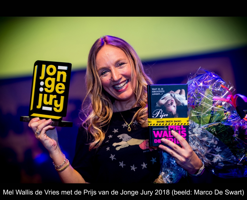 Mel Wallis de Vries met trofee, het winnende boek en bloemen in haar handen.