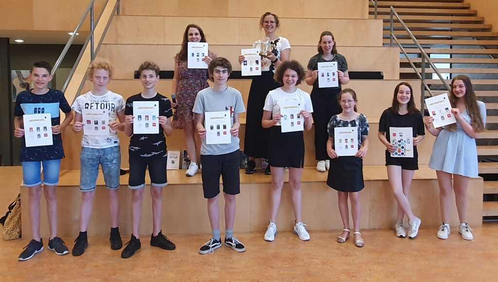 Groepsfoto winnaars De Weddenschap, leerlingen staan voor en op trap met oorkonde,