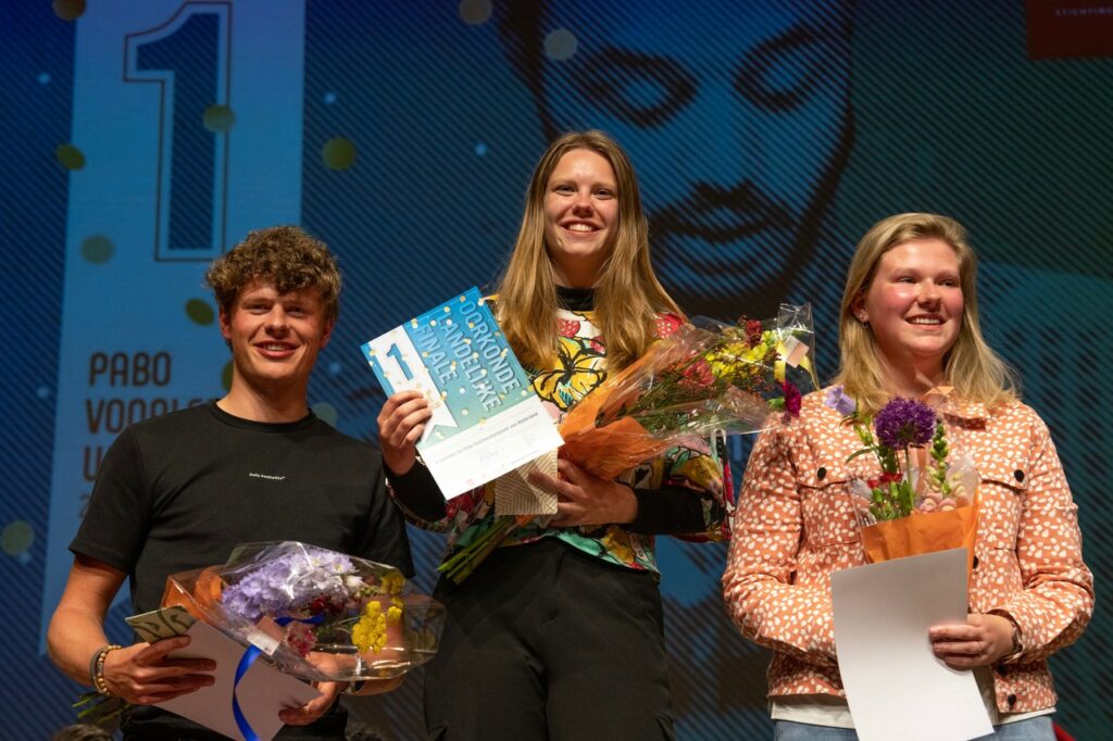 Raoul, Floor en Demi op het podium met bloemen en een oorkonde.