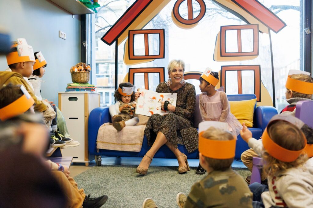 H.K.H Prinses Laurentien leest voor op een voorleestroon. Om haar heen aandachtig luisterende kinderen.