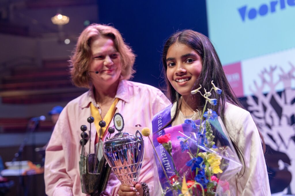 Jayshri Sundaram is De Nationale Voorleeskampioen van 2025. Op het podium met links Rian Visser.