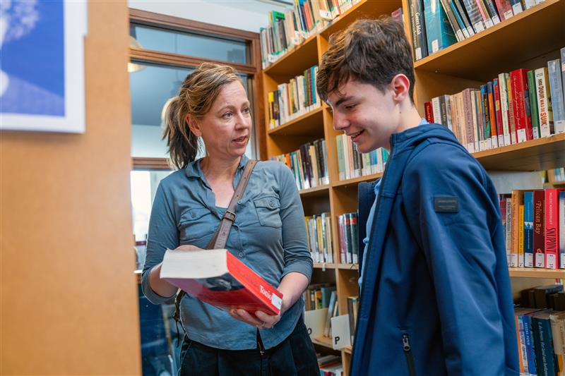 Docent raadt leerling boek aan in mediatheek