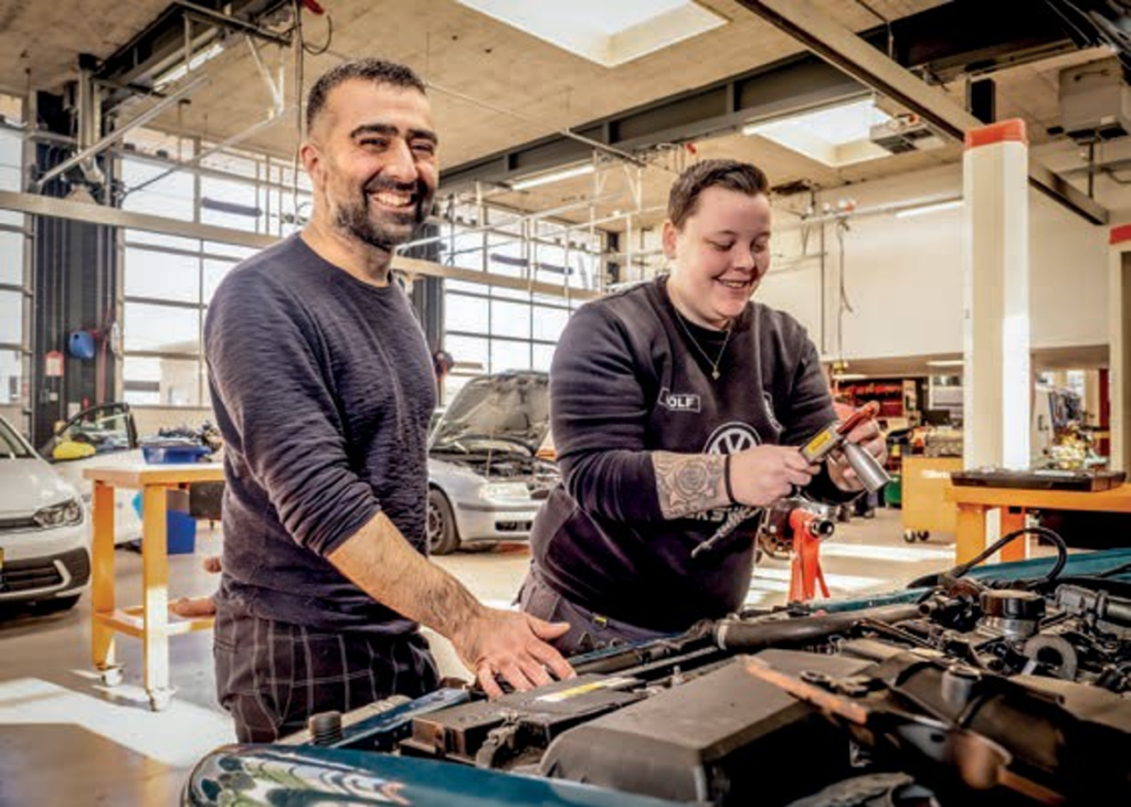 Jaser en een student autotechniek in een garage sleutelend aan een auto