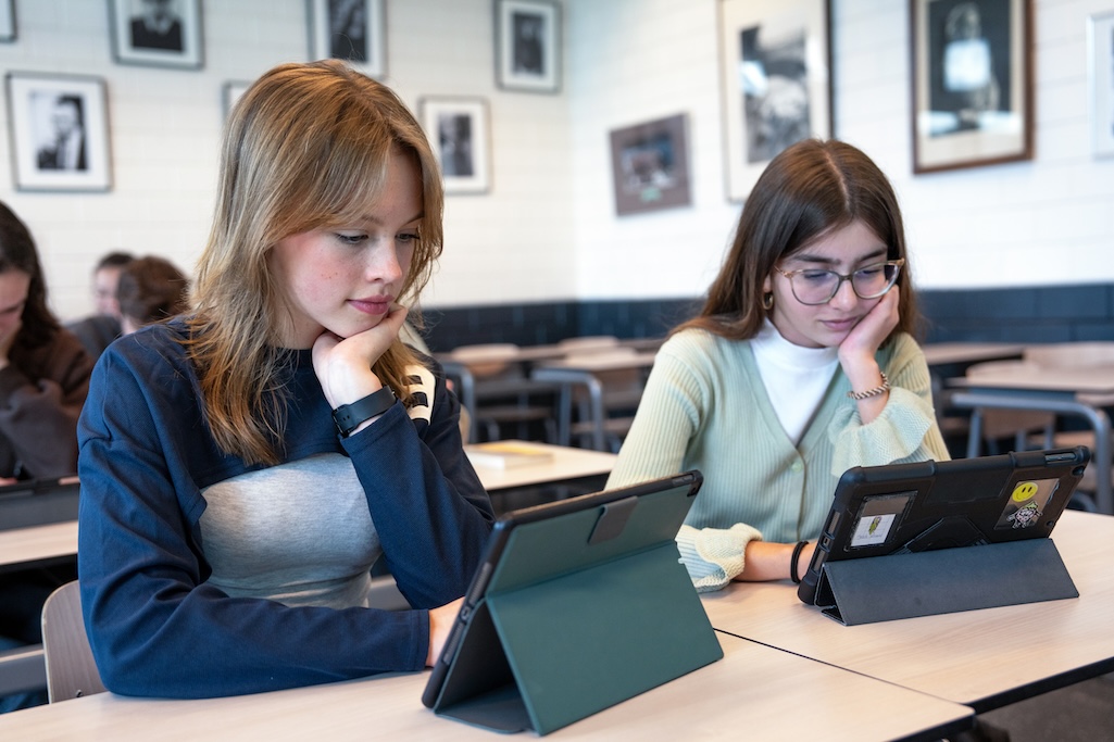 Twee leerlingen kijken naar tablets in de klas.