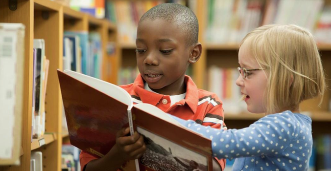 Kinderen lezen boek naast boekenkast